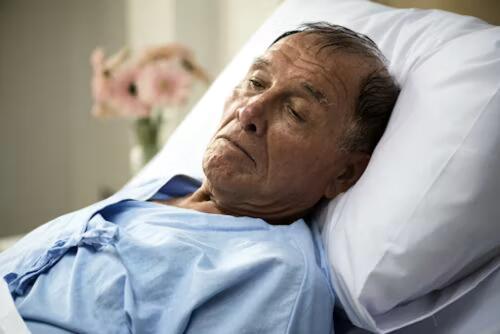 Older man lying in a hospital bed with an IV